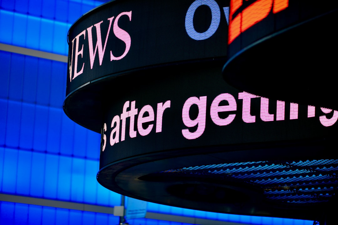 a-close-up-of-a-sign-with-a-building-in-the-background-2oyhdz6lw1w