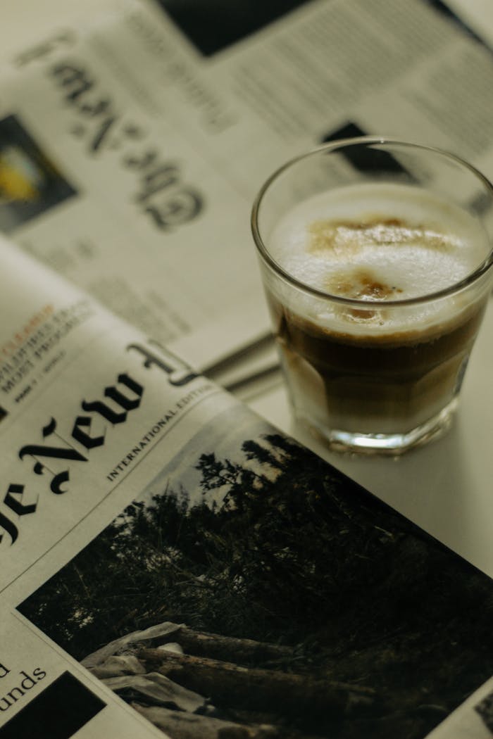 Glass of cappuccino with New York Times newspaper on a cozy morning in New York City.